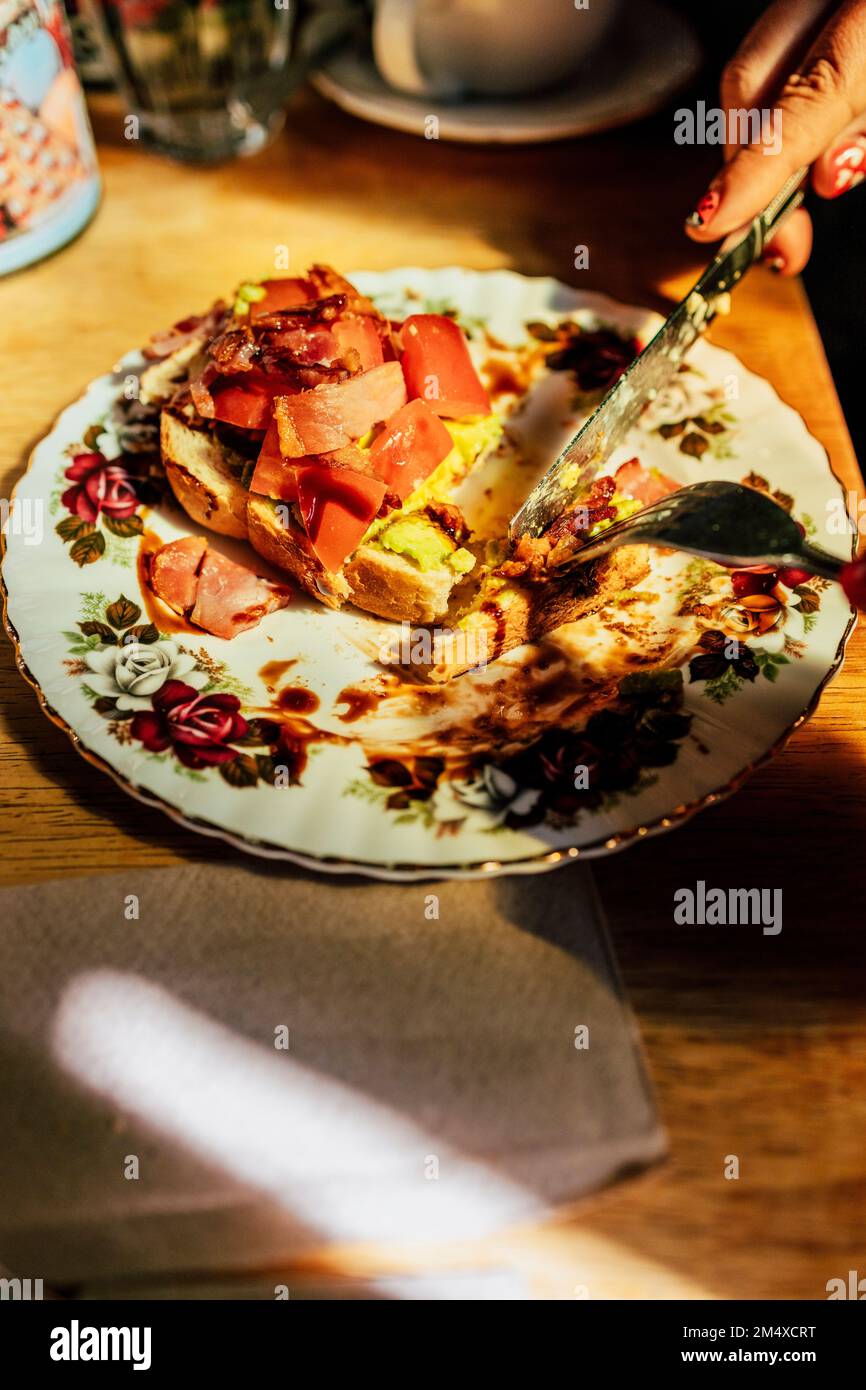 Eine Frau schneidet mit einem Messer am Tisch Essen Stockfoto