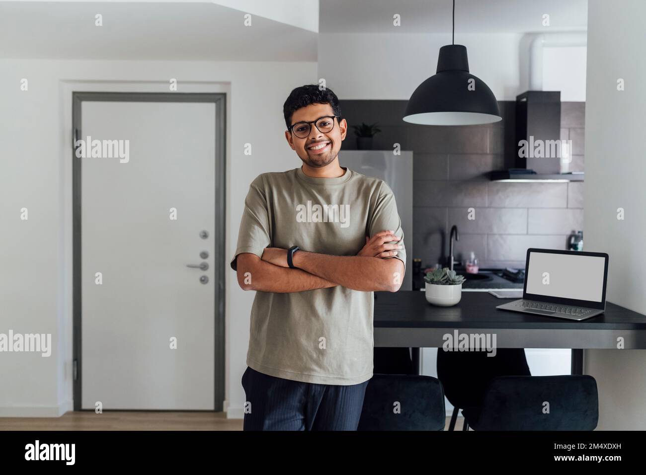 Lächelnder junger Mann mit zu Hause verschränkten Armen Stockfoto