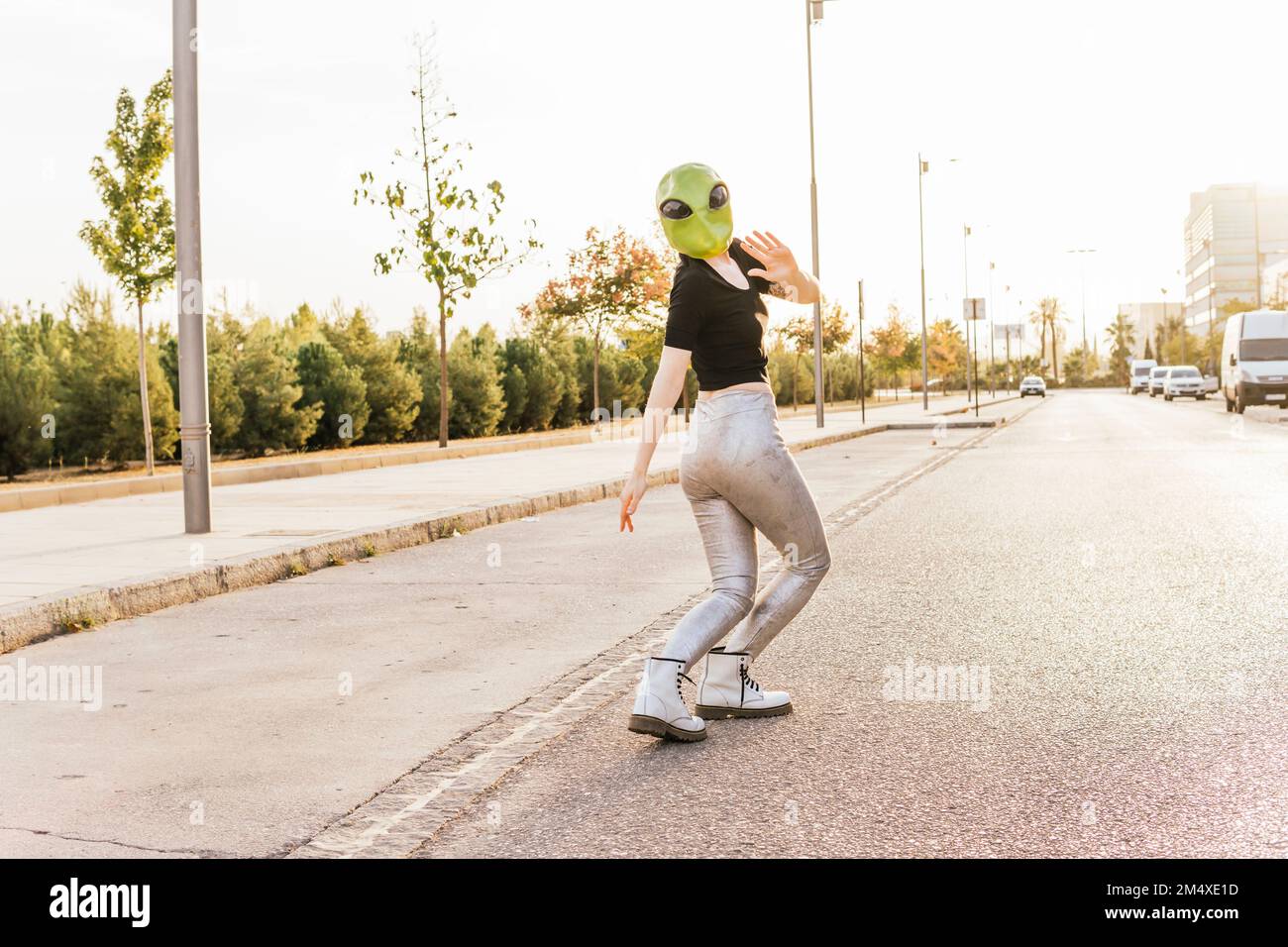 Eine Frau mit Alien-Maske, die auf der Straße winkt Stockfoto