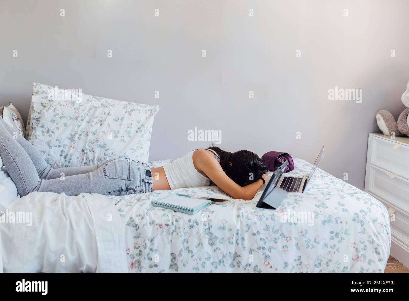 Ein Mädchen schläft mit kabelloser Technologie zu Hause im Bett Stockfoto