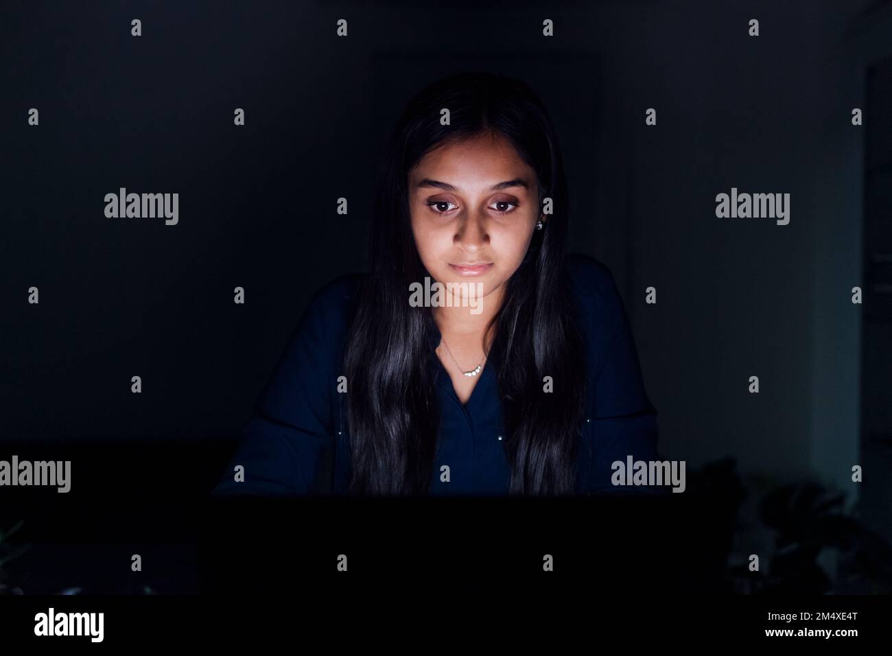 Beleuchtete junge Frau im dunklen Raum Stockfoto