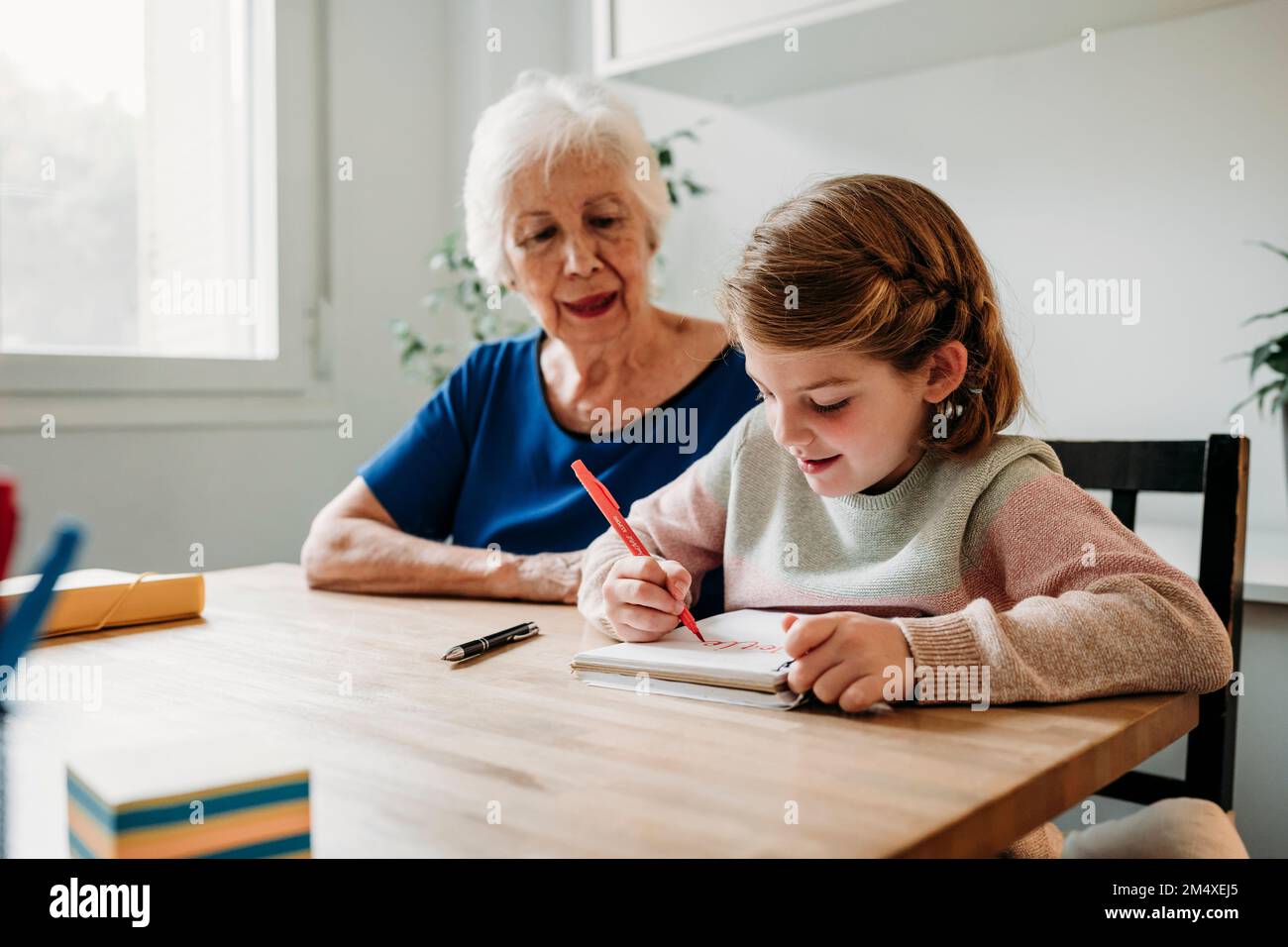Großmutter hilft Mädchen beim Lernen auf Tisch zu Hause Stockfoto