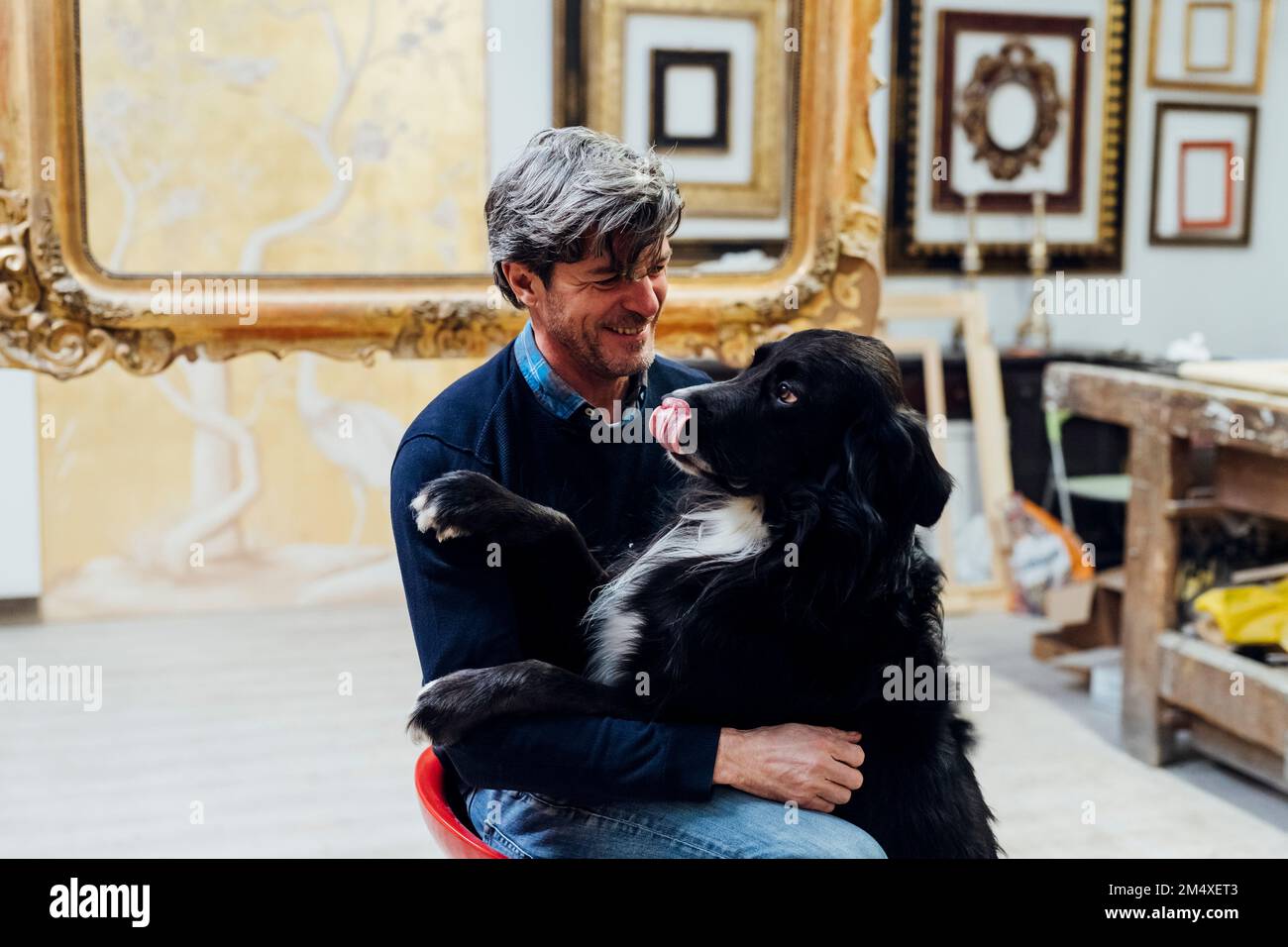 Glücklicher Mann mit schwarzem Hund in der Werkstatt Stockfoto