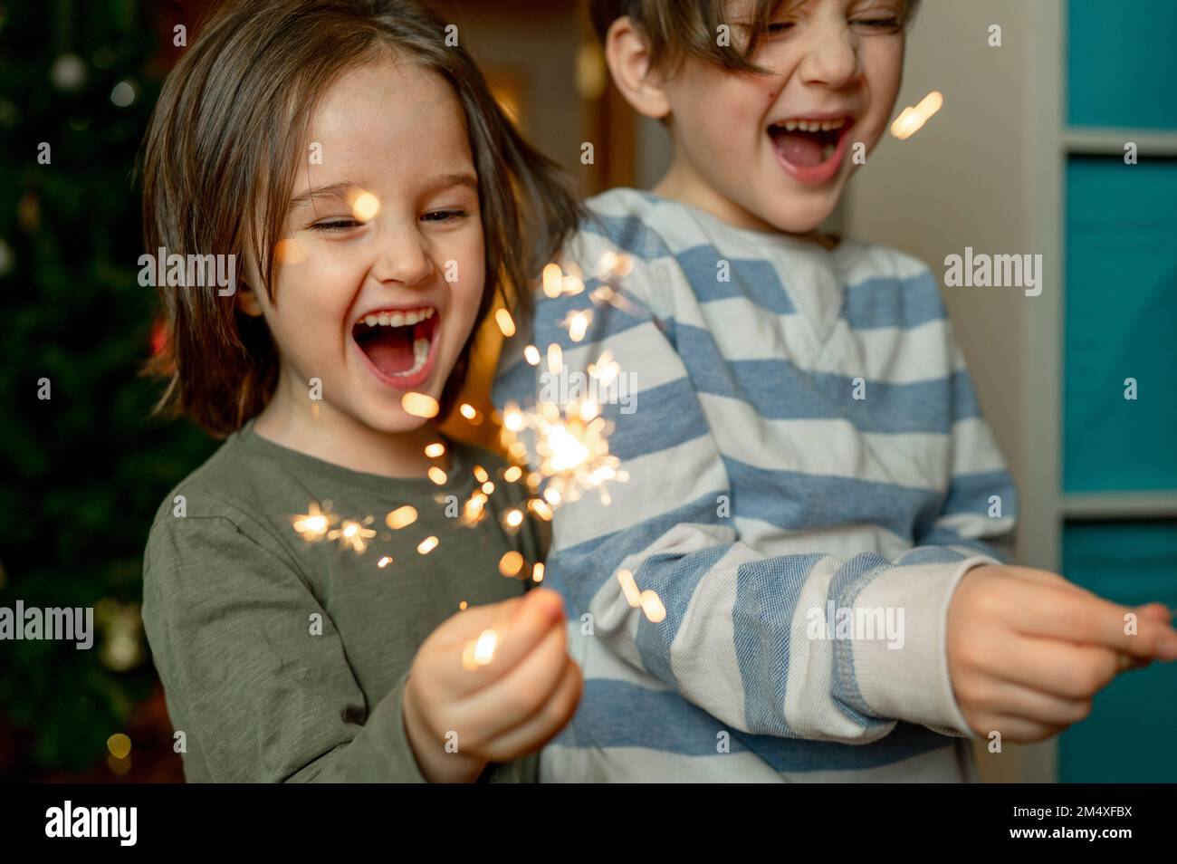 Fröhliche Brüder, die zu Hause brennenden Sparkler halten Stockfoto