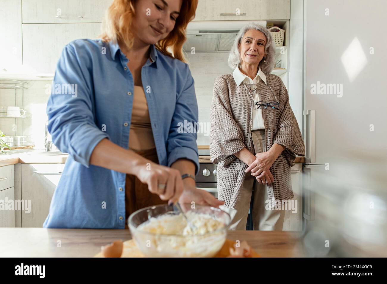 Seniorin und Erwachsene Tochter bereiten Teig für Brot in der Küche zu Stockfoto