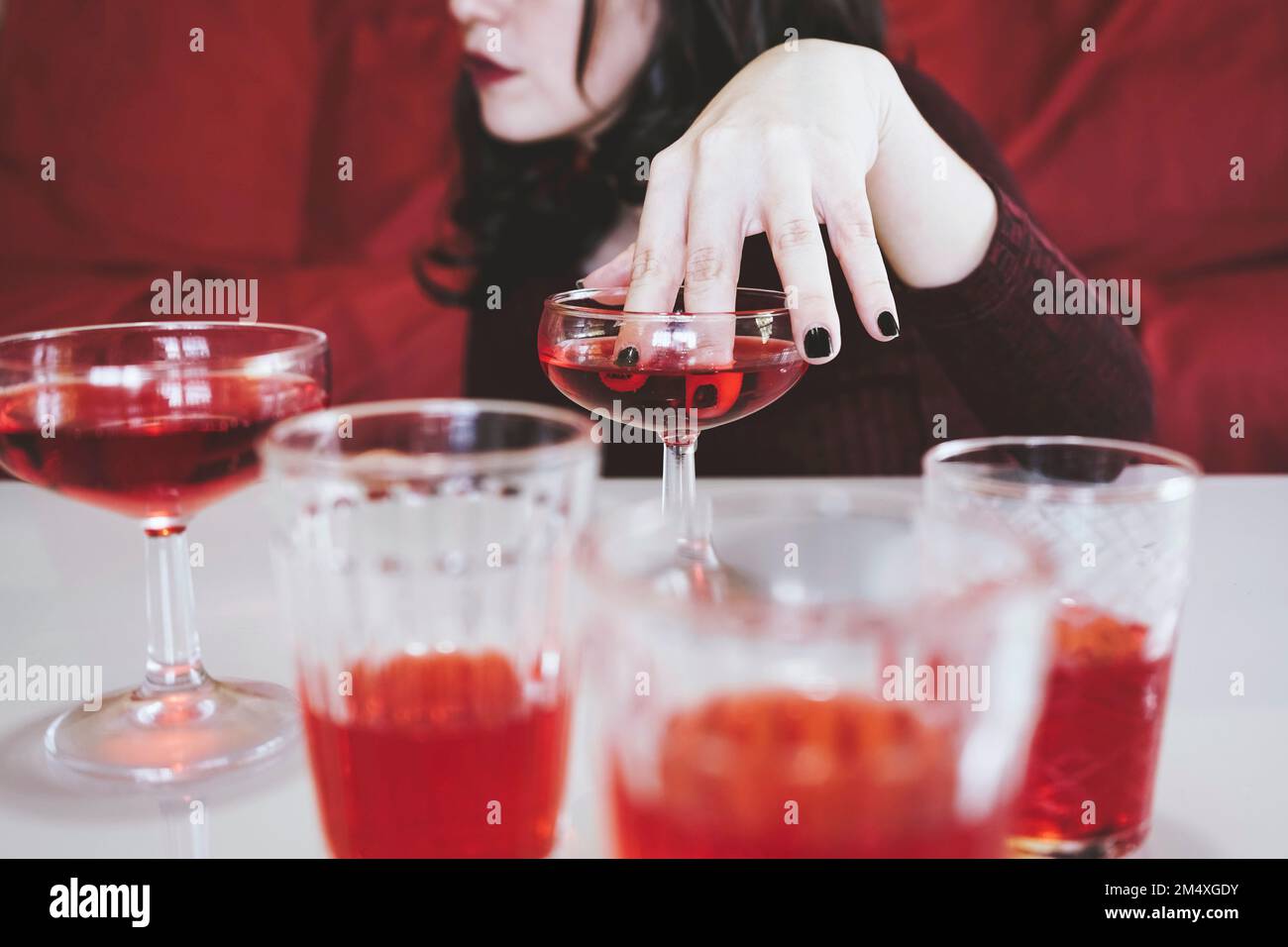 Eine Frau, die Finger in einen roten Alkohol taucht Stockfoto