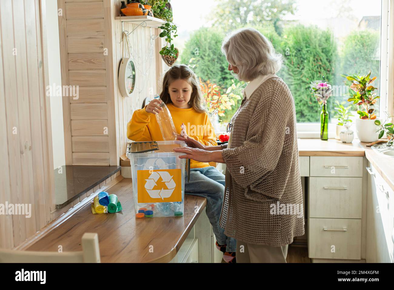 Großmutter und Enkelin sortieren Abfälle in der Küche Stockfoto