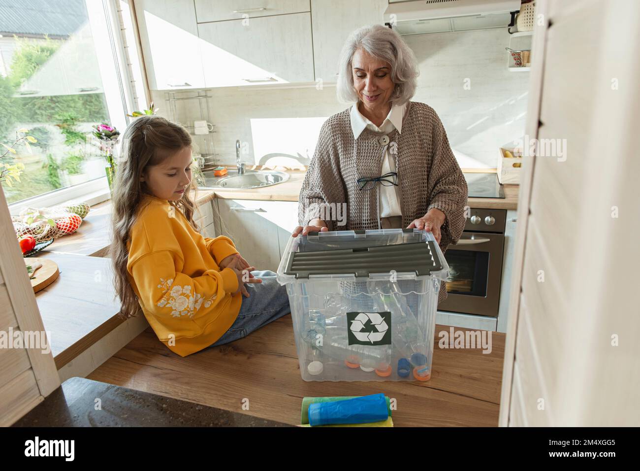 Großmutter und Enkelin sortieren Abfälle in der Küche Stockfoto