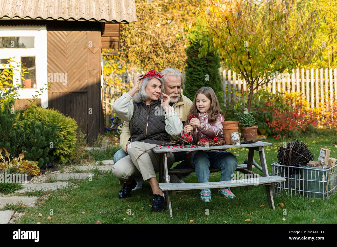 Großeltern und Enkelin sitzen am Gartentisch und machen mit Bergreste Stockfoto