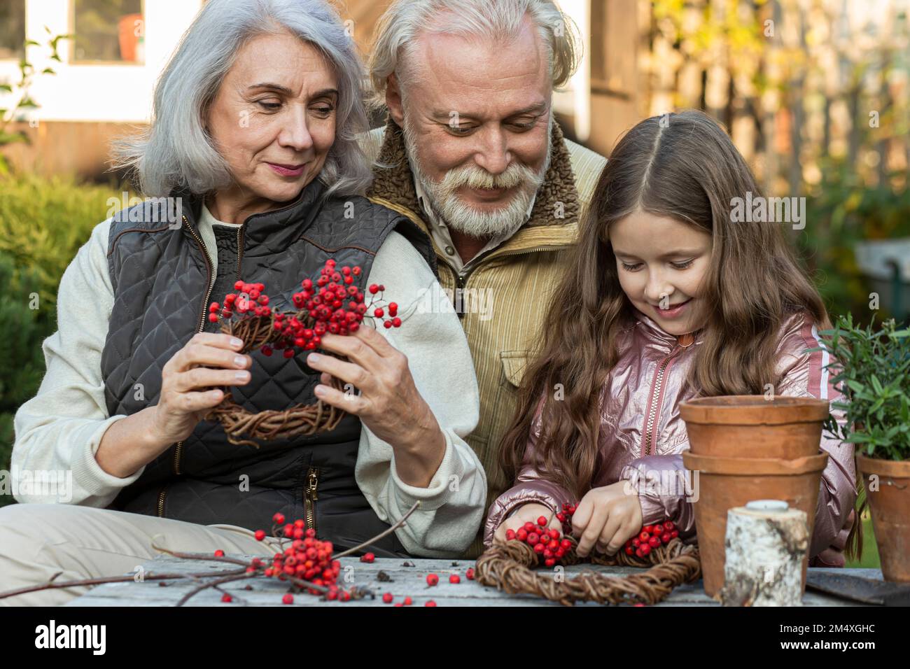 Großeltern und Enkelin sitzen am Gartentisch und machen mit Bergreste Stockfoto