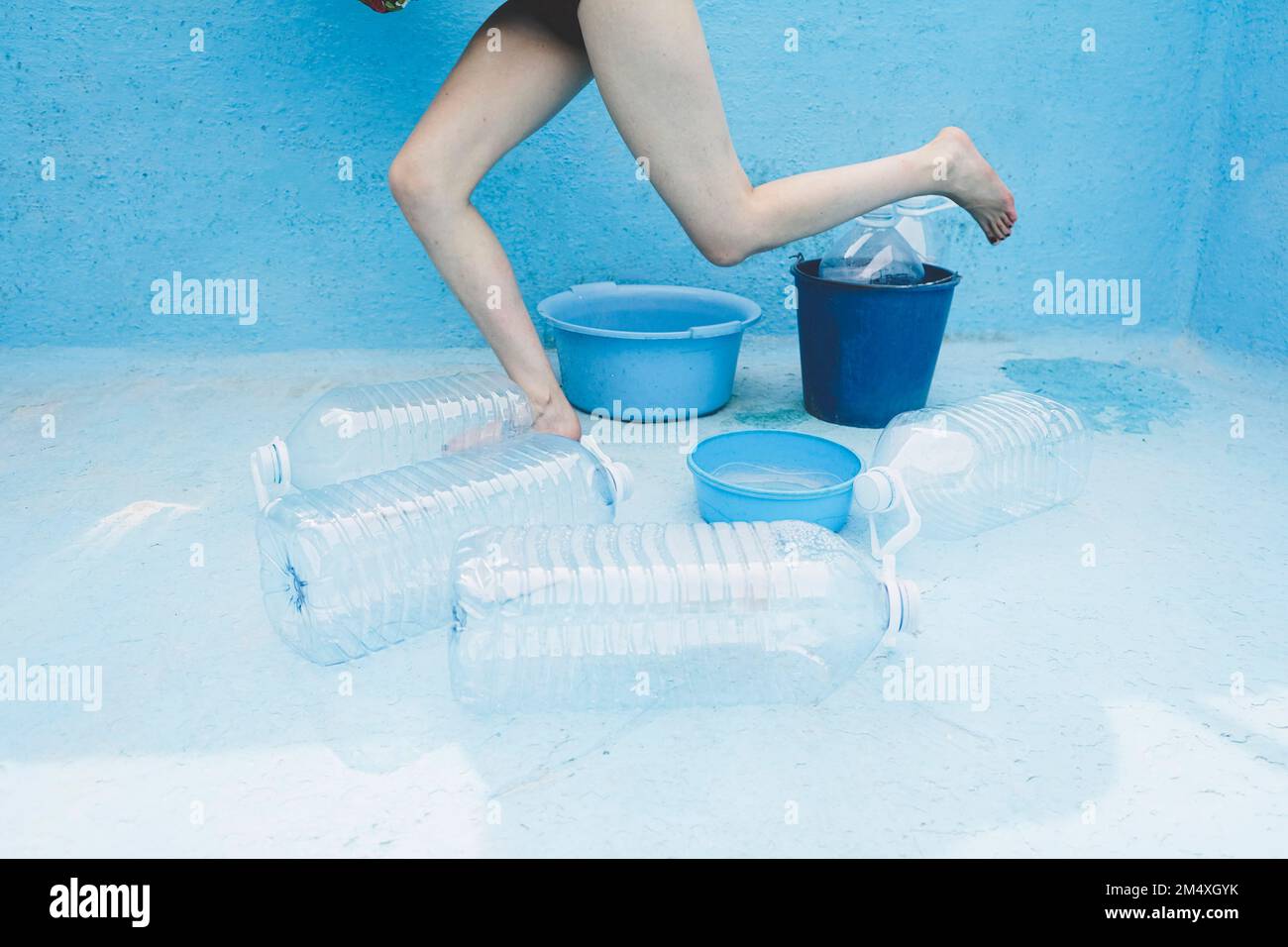 Frau inmitten von Plastikflaschen und Eimern im leeren Pool Stockfoto