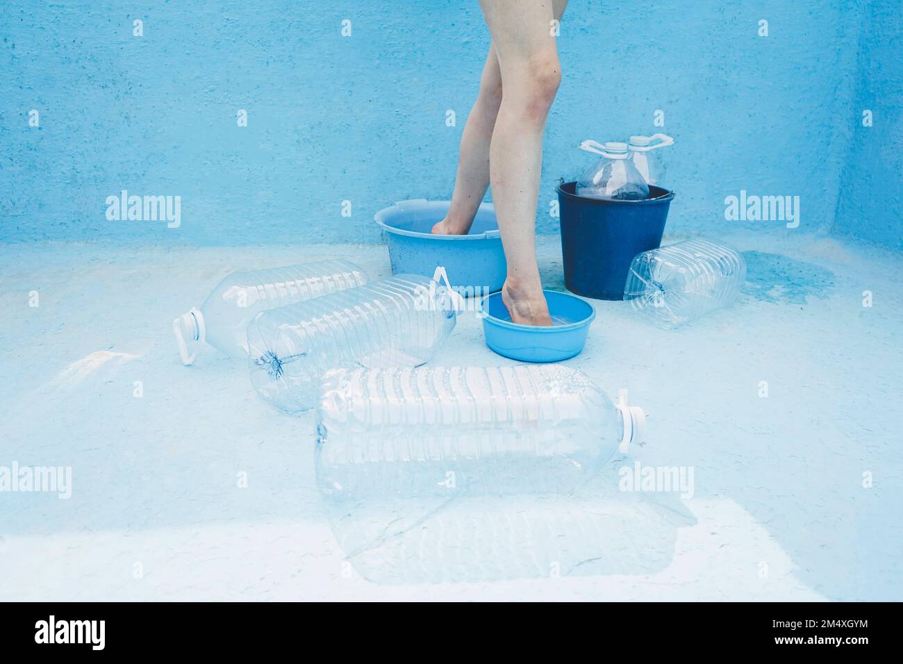 Eine Frau, die in leeren Eimern im Schwimmbad steht Stockfoto