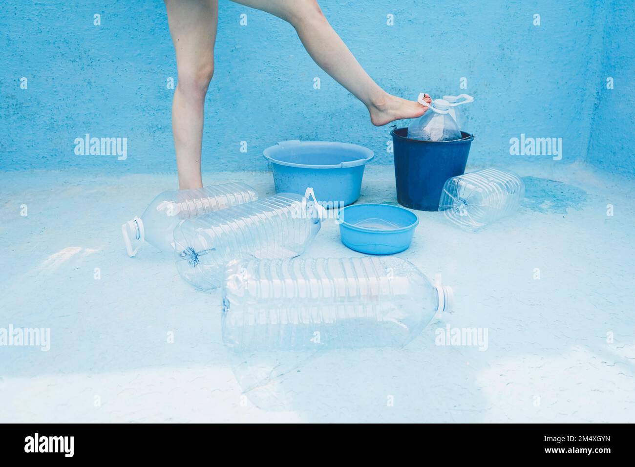 Eine Frau steht neben einer Plastikflasche im leeren Pool Stockfoto