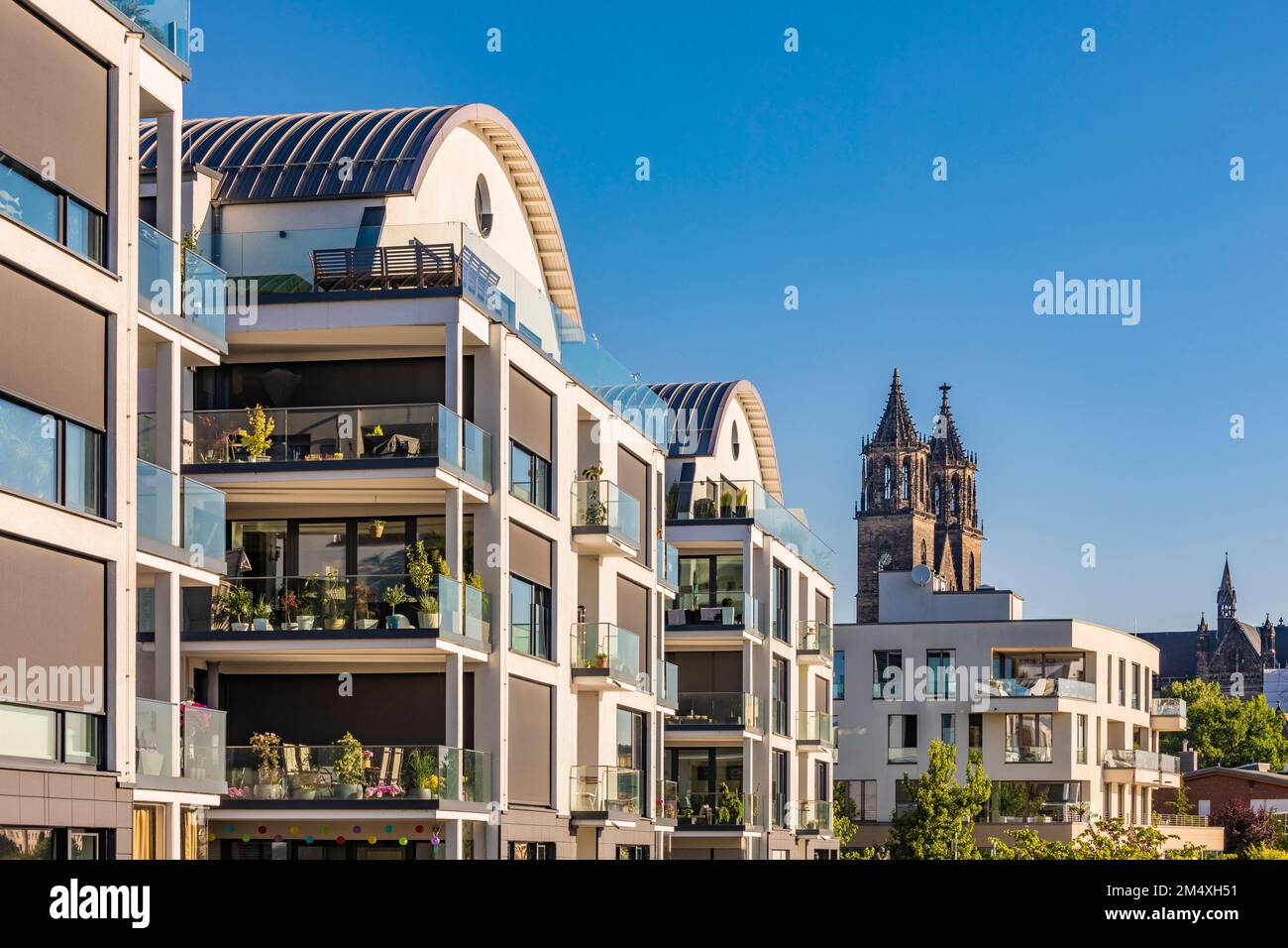 Deutschland, Sachsen-Anhalt, Magdeburg, moderne Apartments mit Glockentürmen des Magdeburger Doms im Hintergrund Stockfoto