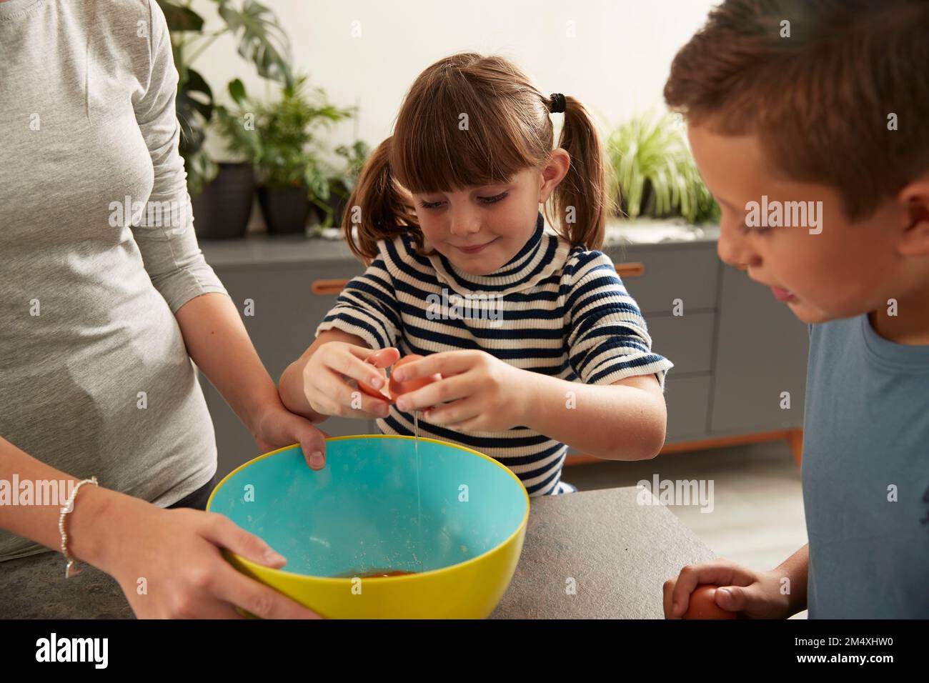 Lächelndes Mädchen, das Schwester hilft, Kekse von Bruder zuhause zuzubereiten Stockfoto