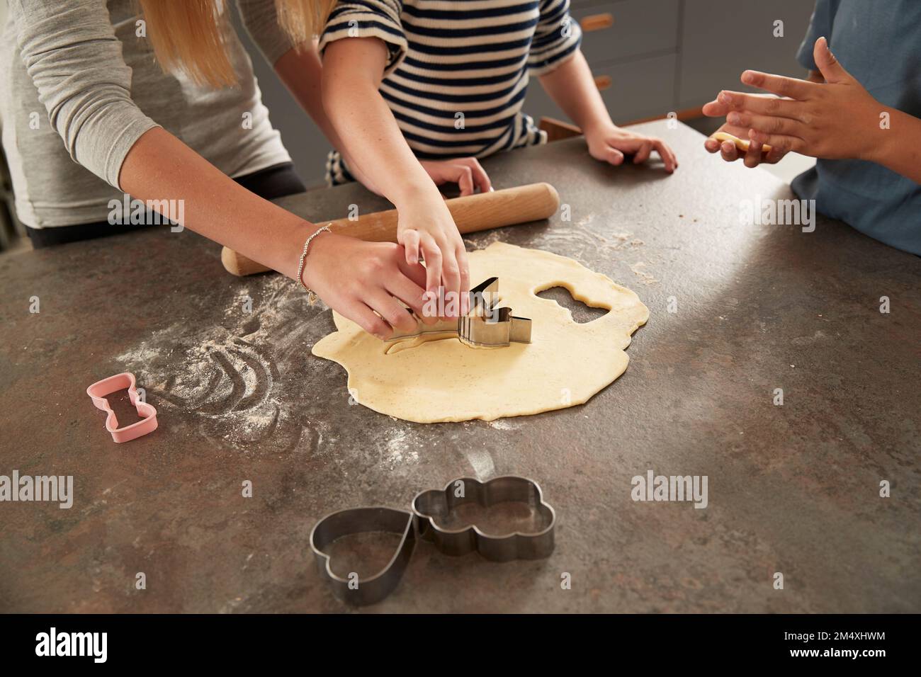 Kinderhände mit Keksschneider an der Küchentheke Stockfoto