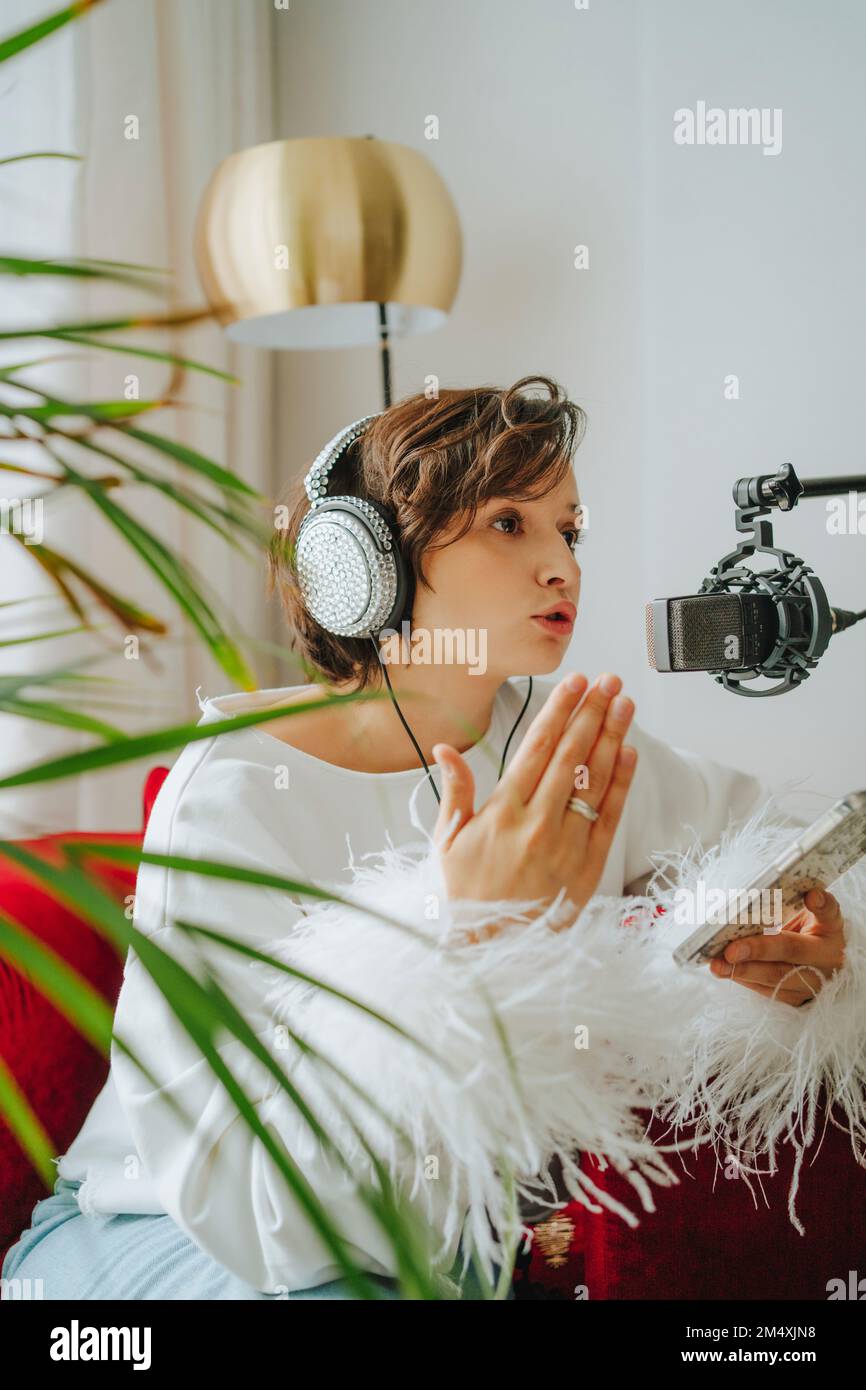 Musiker mit Kopfhörern, der im Studio Podcasts von Mobiltelefonen aufnimmt Stockfoto