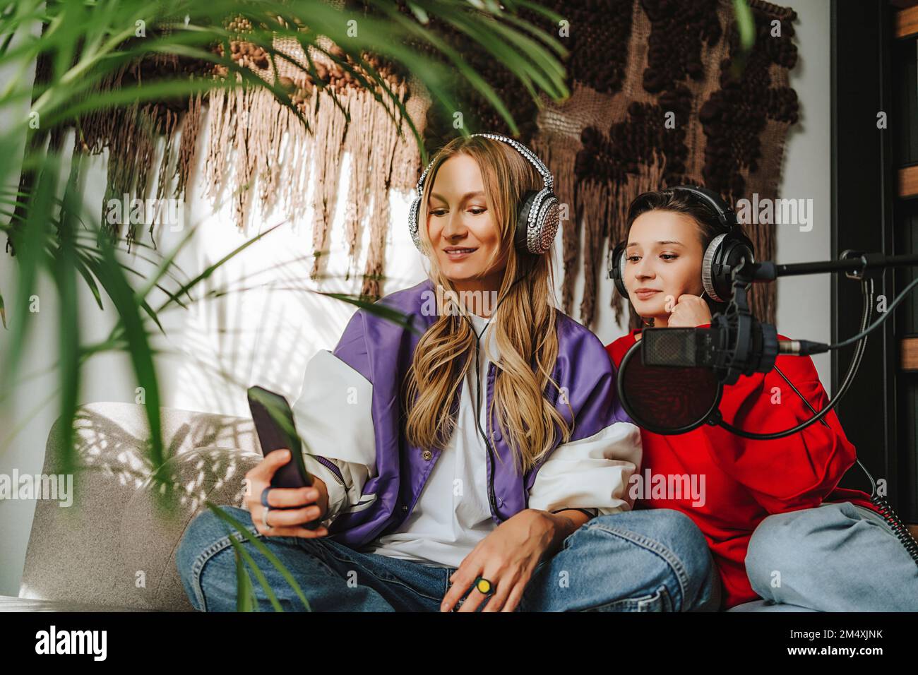 Lächelnder Musiker mit einem Kollegen, der Kopfhörer trägt und Selfie über das Mobiltelefon im Studio macht Stockfoto