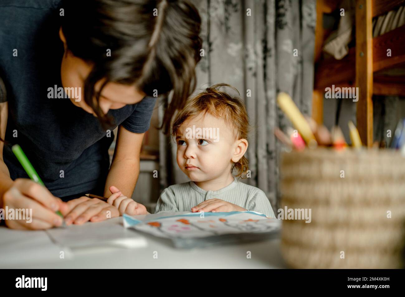 Trauriger kleiner Junge von Bruder, der zu Hause mit Stift schreibt Stockfoto