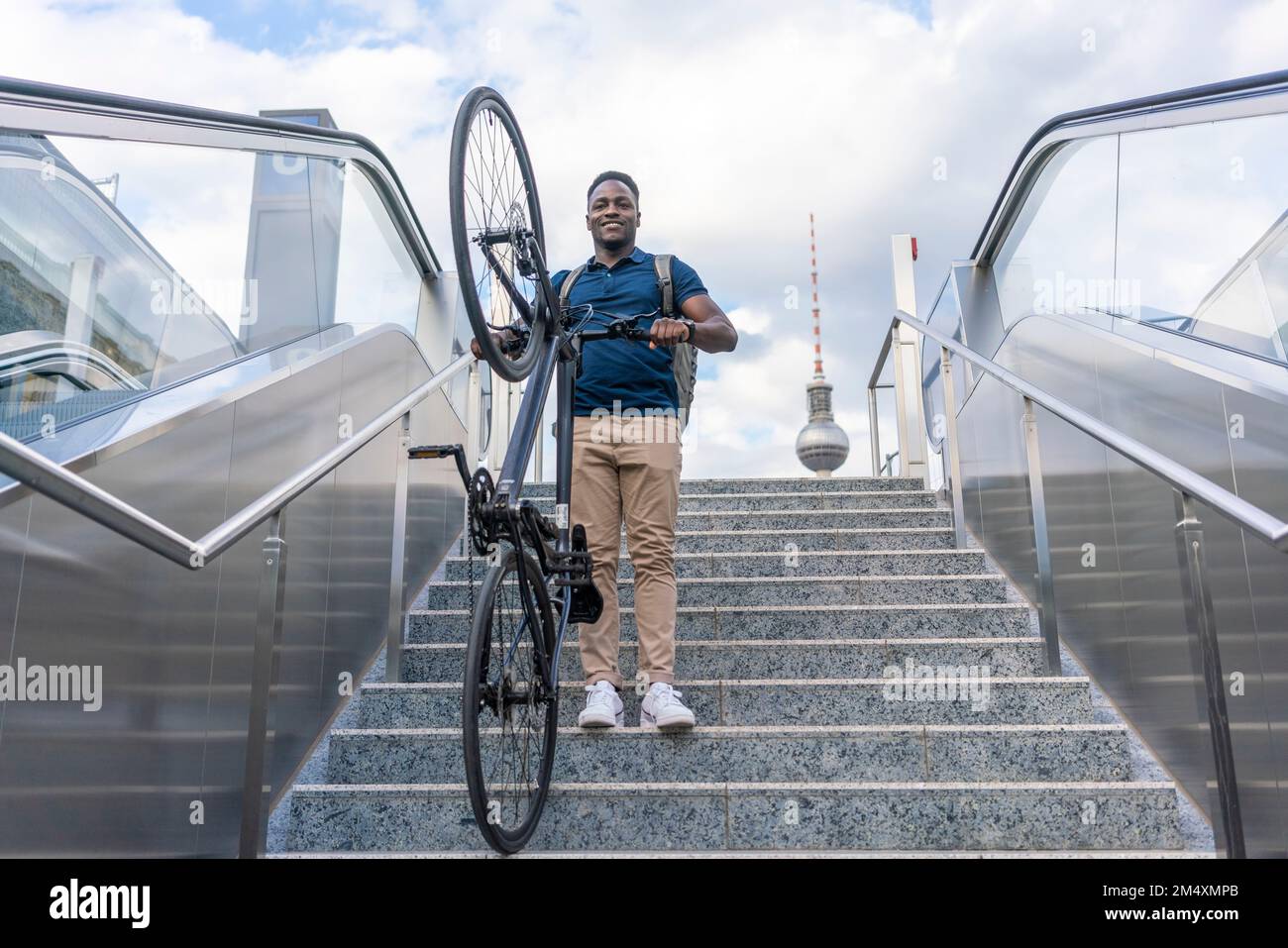 Ein verspielter Mann, der ein Fahrrad auf der Treppe trägt Stockfoto