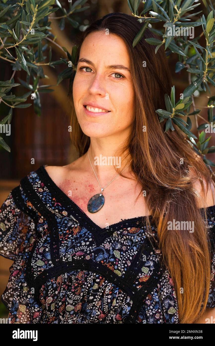 Lächelnde Frau mit braunen Haaren im Garten Stockfoto