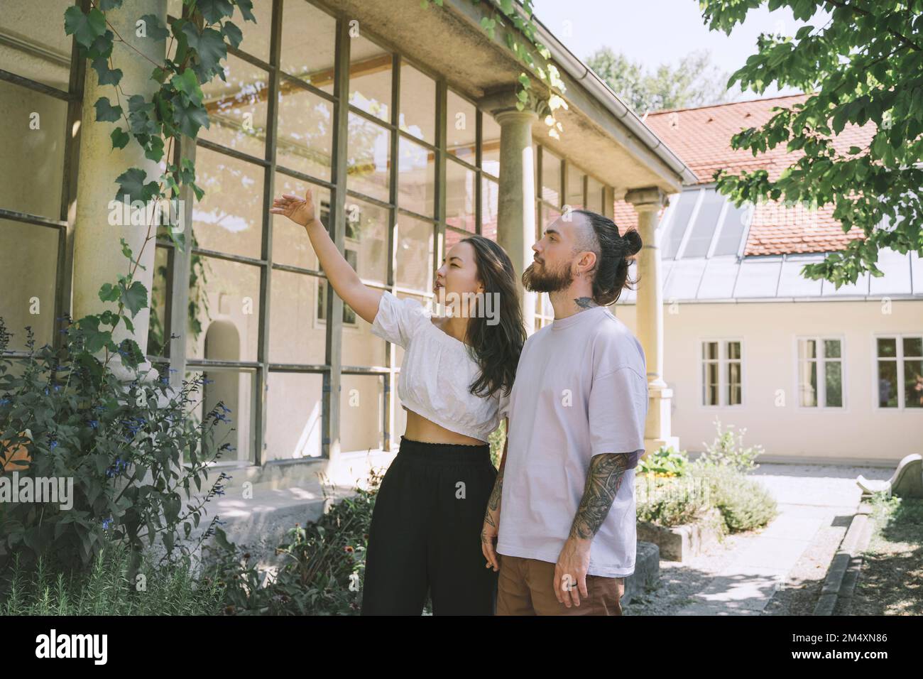 Ein Hipsterpaar, das Pflanzen vor dem Haus untersucht Stockfoto