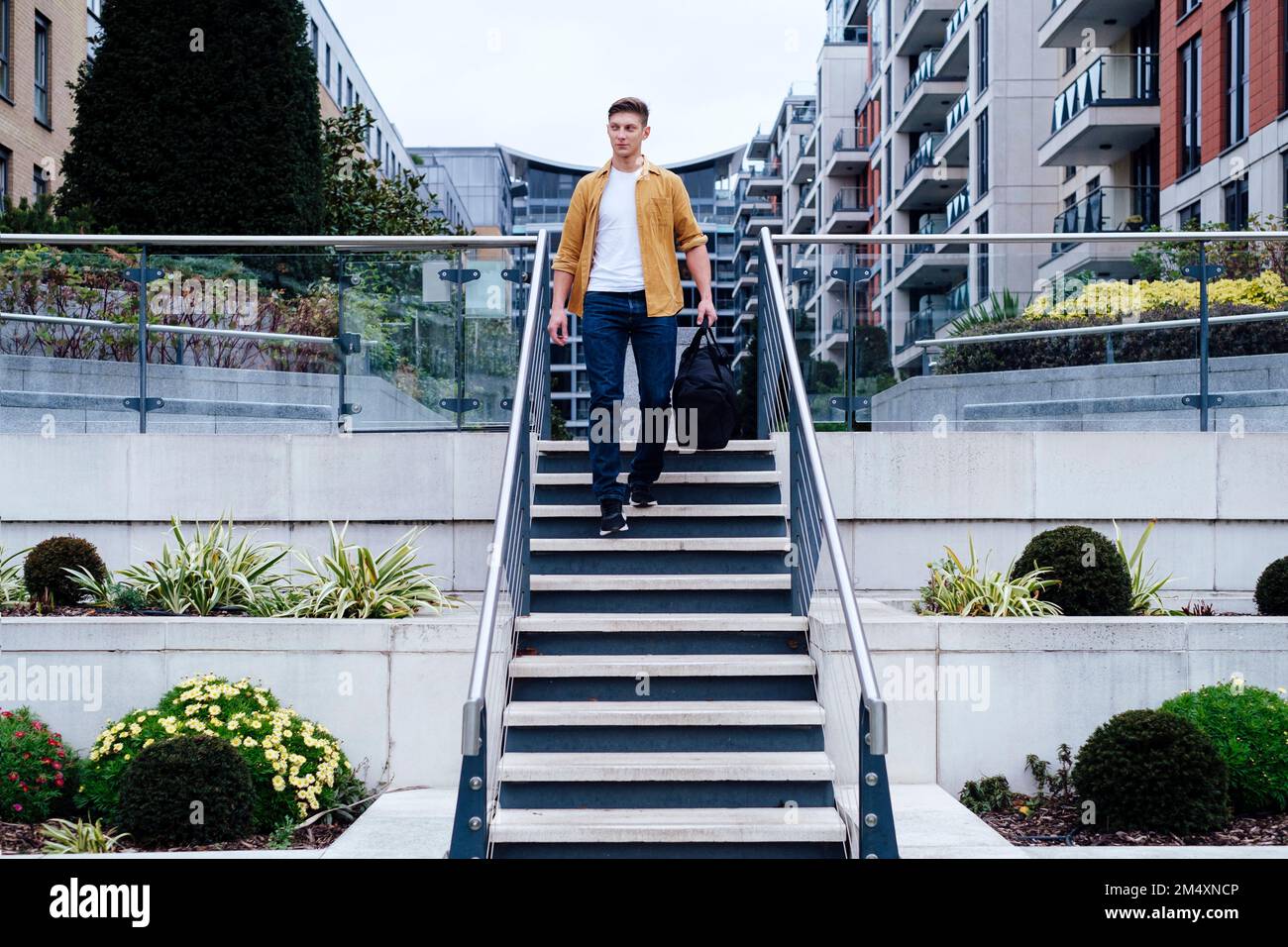 Junger Mann mit Tasche, der die Treppe runtergeht Stockfoto