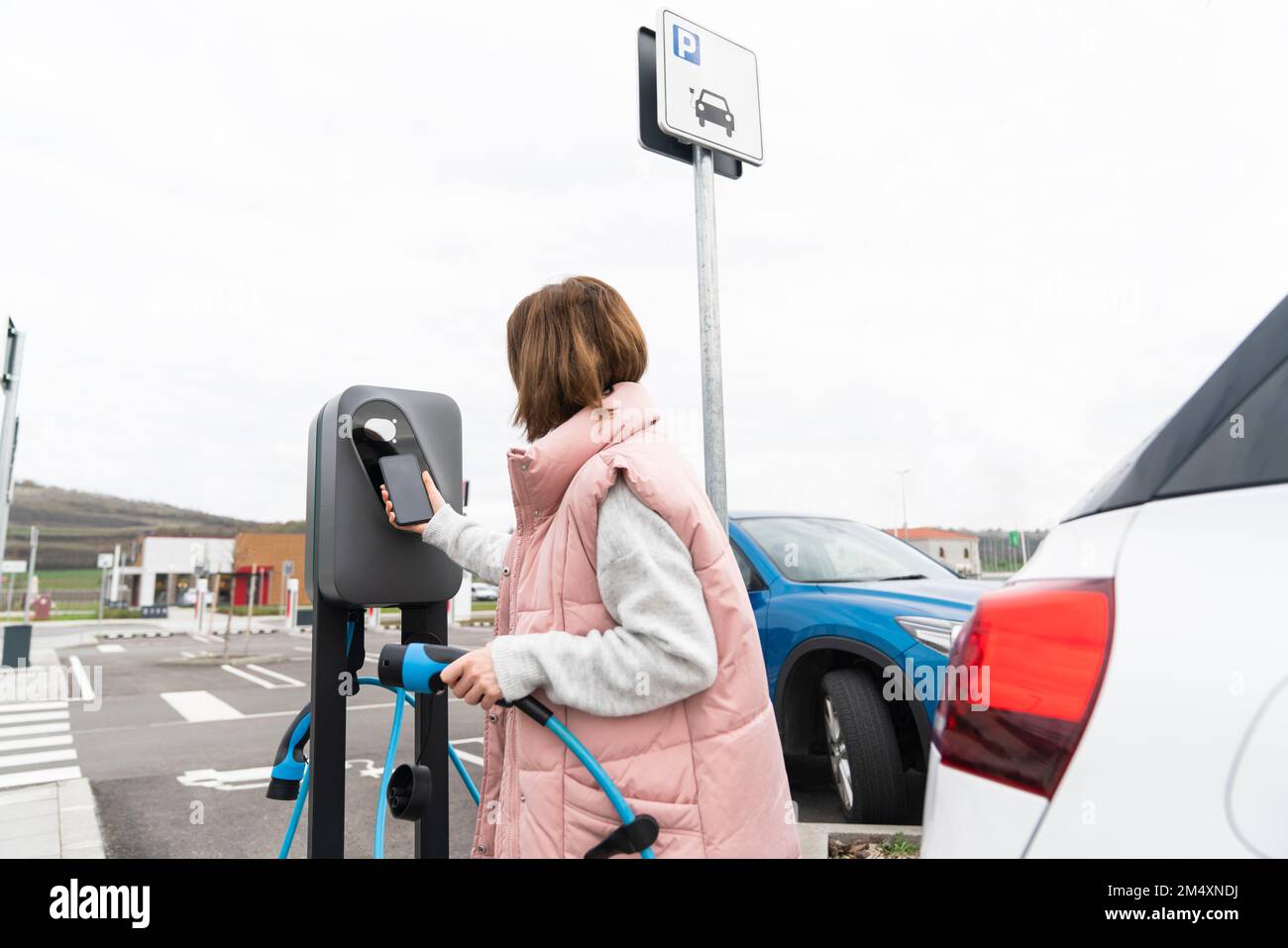 Frau, die an der Ladestation ein Smartphone durchsucht Stockfoto