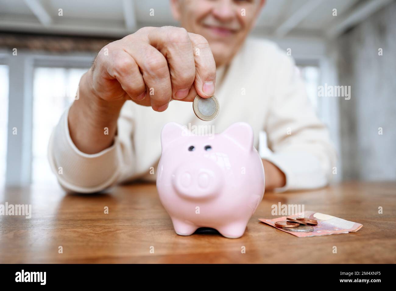 Ein Mann, der zu Hause Geld in die Sparschweinbank steckt Stockfoto