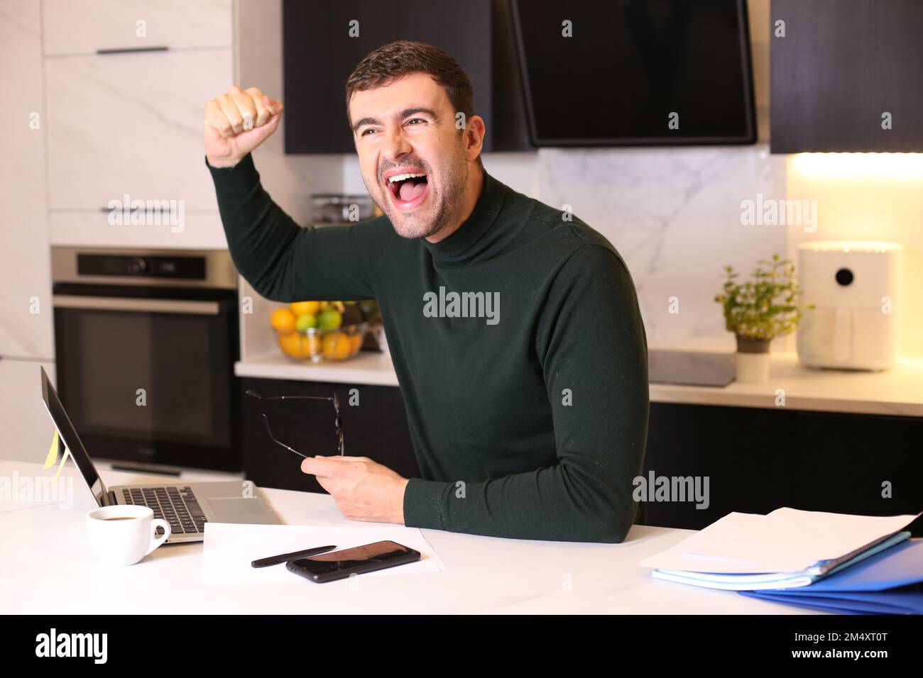 Ein Mann, der einen Sieg vom Heimbüro aus feiert Stockfoto