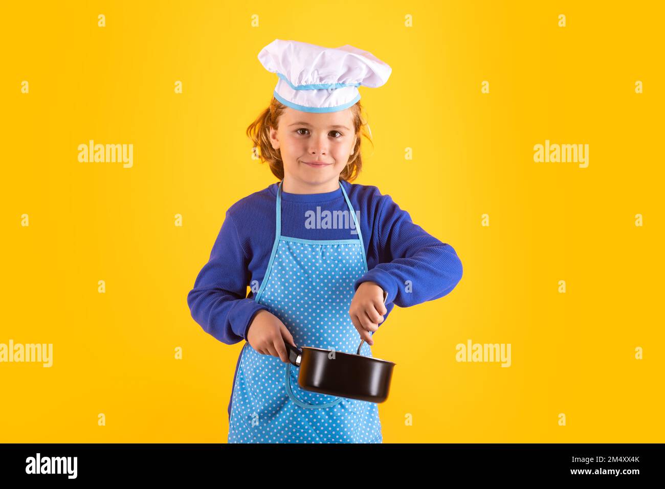 Kinderkoch kocht mit Kochtopf. Koch Kind bereitet gesundes Essen zu. Studioporträt eines Kindes mit Koch-Hüten. Stockfoto