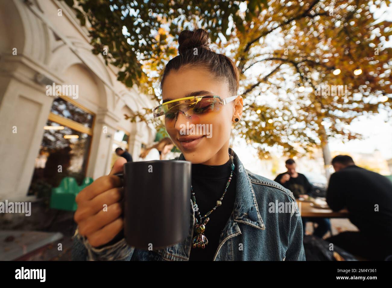 Nette junge Frau beim Tee trinken im modernen Straßencafé Stockfoto