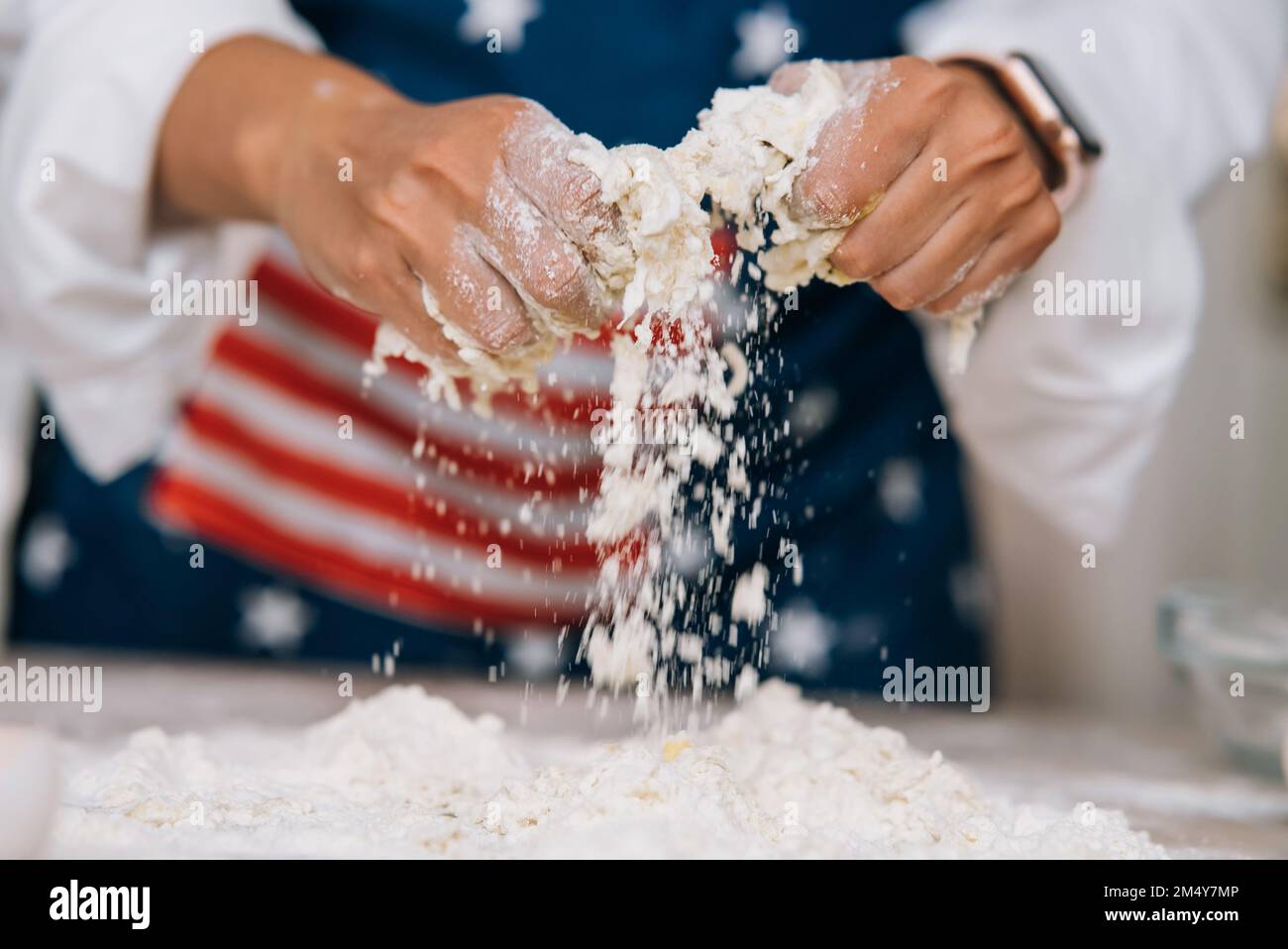 Die junge Hausfrau knetet mit ihren Händen auf einer Schürze Teig. Stockfoto