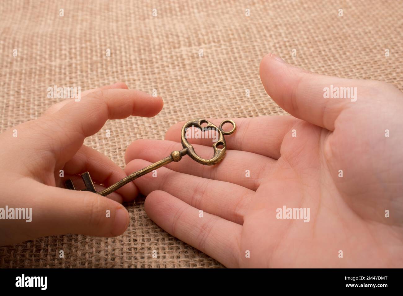 Hand mit einem goldenen Schmuckschlüssel im Retro-Stil Stockfoto