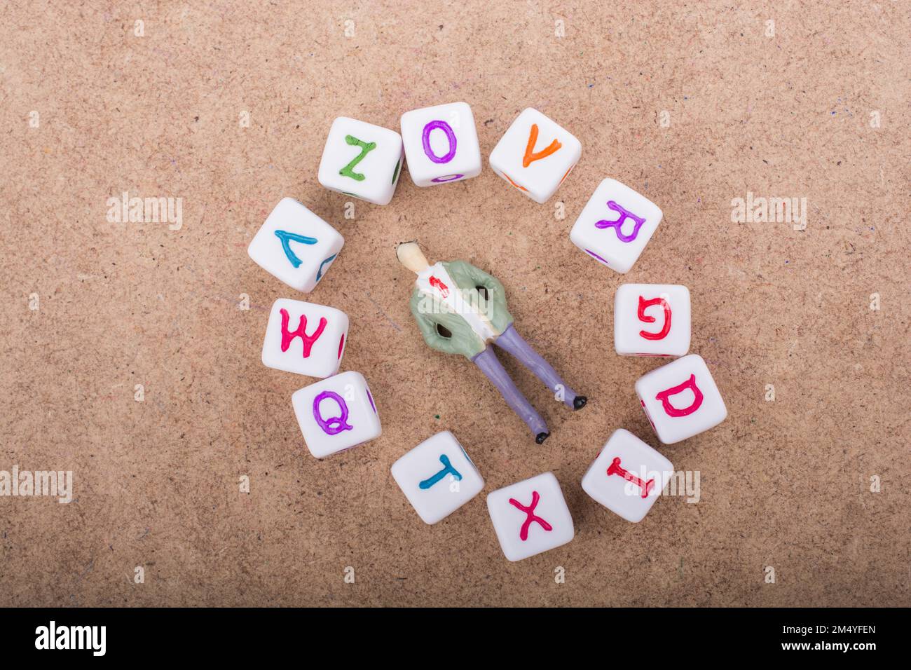 Die Figur ruht in der Mitte des Kreises, der aus Buchstabenwürfeln gebildet wird Stockfoto