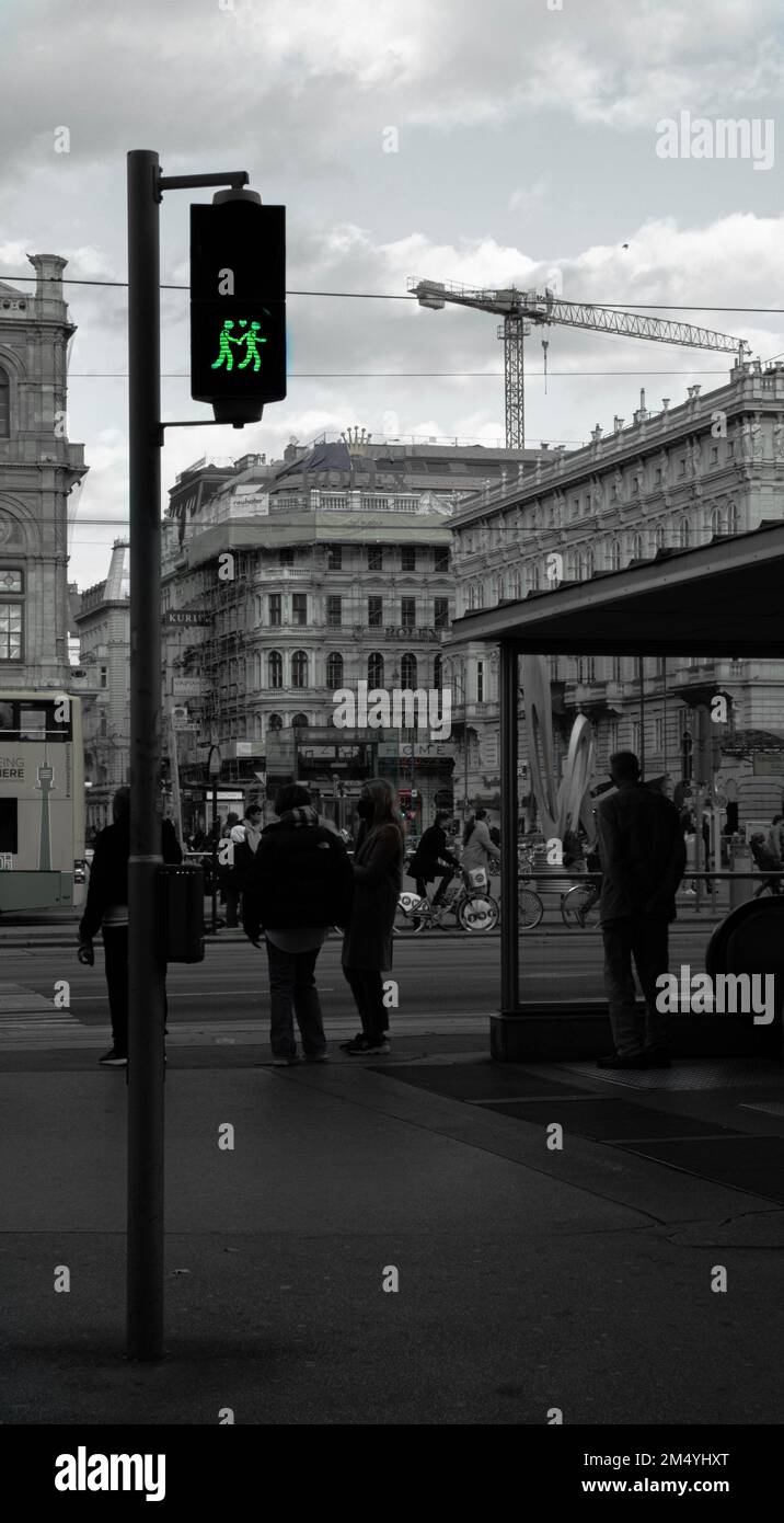 Eine vertikale Graustufenaufnahme einer Ampel mit grünen menschlichen Ikonen, die Händchen halten. Das Konzept der Liebe. Stockfoto