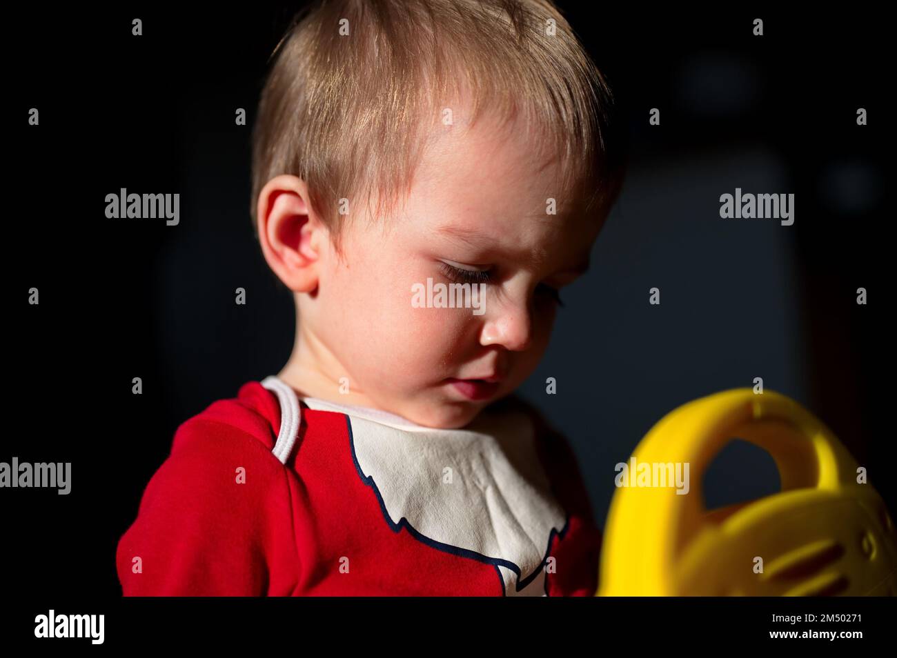 Porträt eines süßen kleinen Jungen in Weihnachtsmannkleidung, der mit gelbem Spielzeug spielt Stockfoto