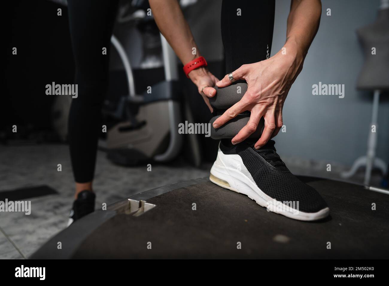 Nahaufnahme zu Fuß einer unbekannten Weißen, die Knöchelgewicht auf das Schienbein legt, bereite dich auf das Training vor Stockfoto