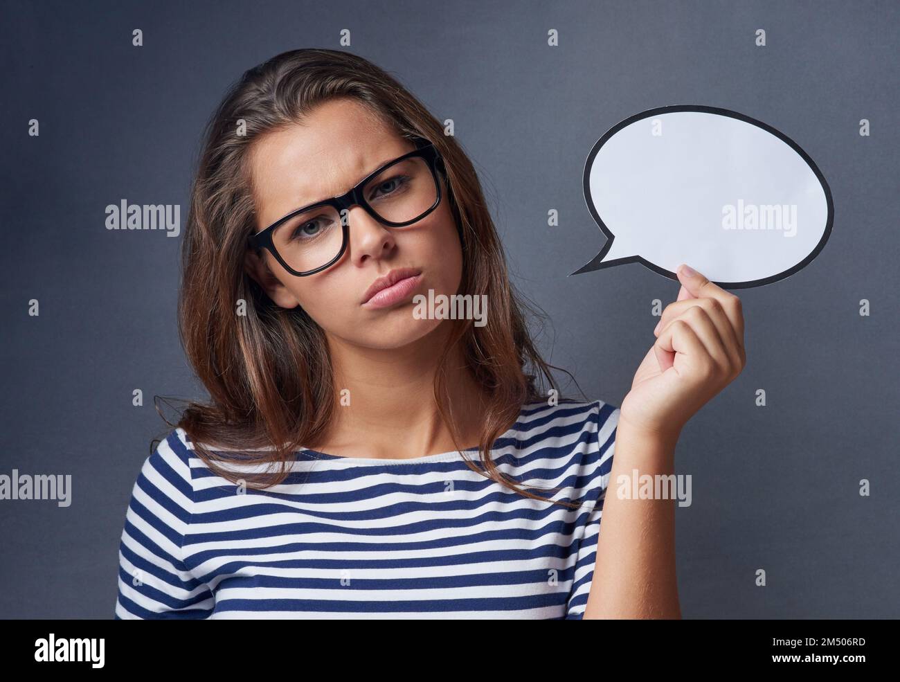 Wenn ich wütend bin, wirst du davon hören. Studiofoto einer attraktiven jungen Frau, die eine leere Sprechblase hält und wütend vor grauem Hintergrund aussieht Stockfoto