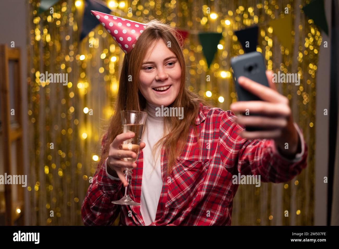 Porträt einer fröhlichen lächelnden Frau, die beim Geburtstagsfeiern lacht und abends bei einem Videoanruf zu Hause mit Champagnerglas spricht. C Stockfoto