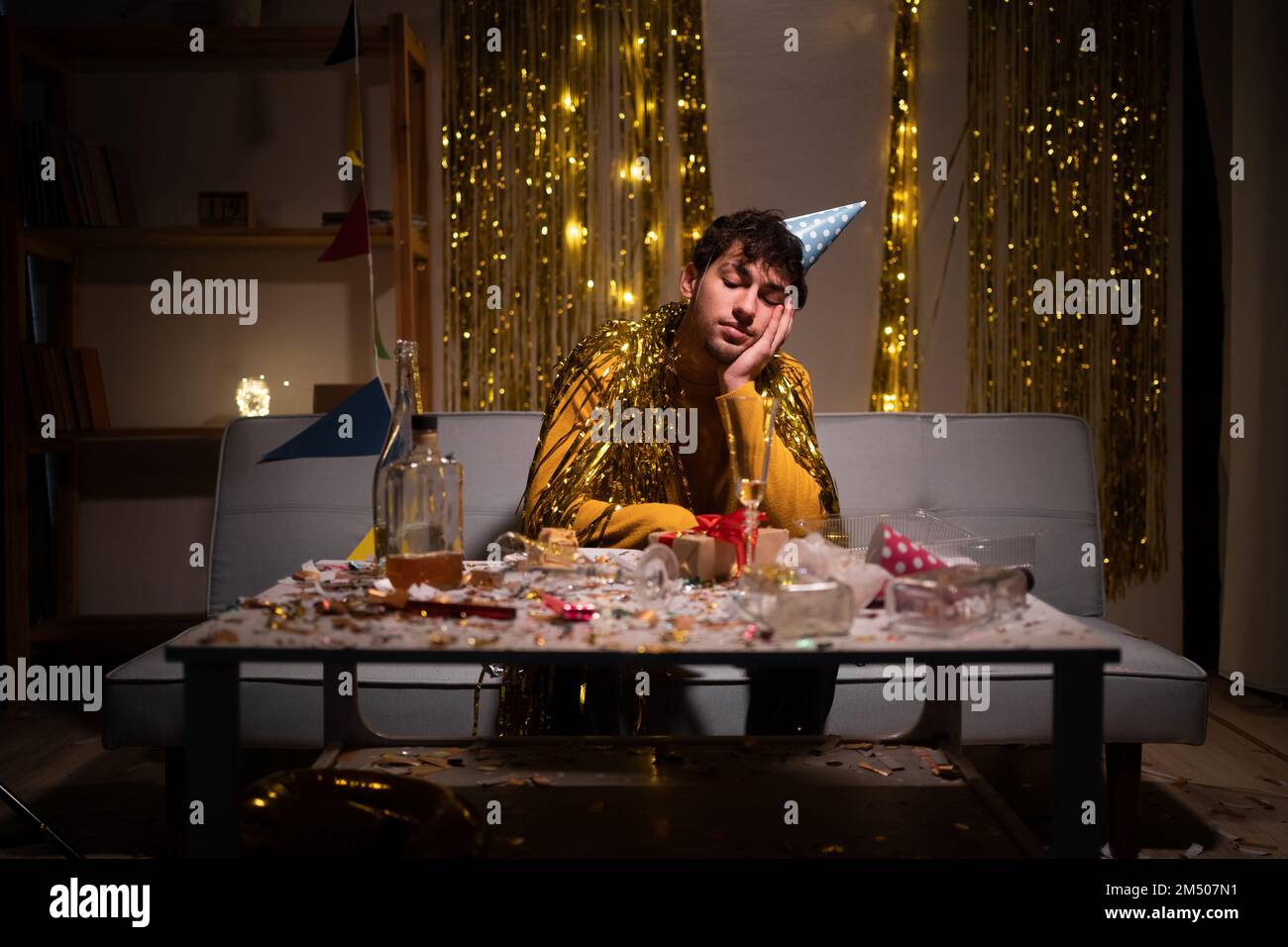 Ein müder betrunkener Mann nach einer Party zu Hause, der auf dem Sofa sitzt. Speicherplatz kopieren Stockfoto