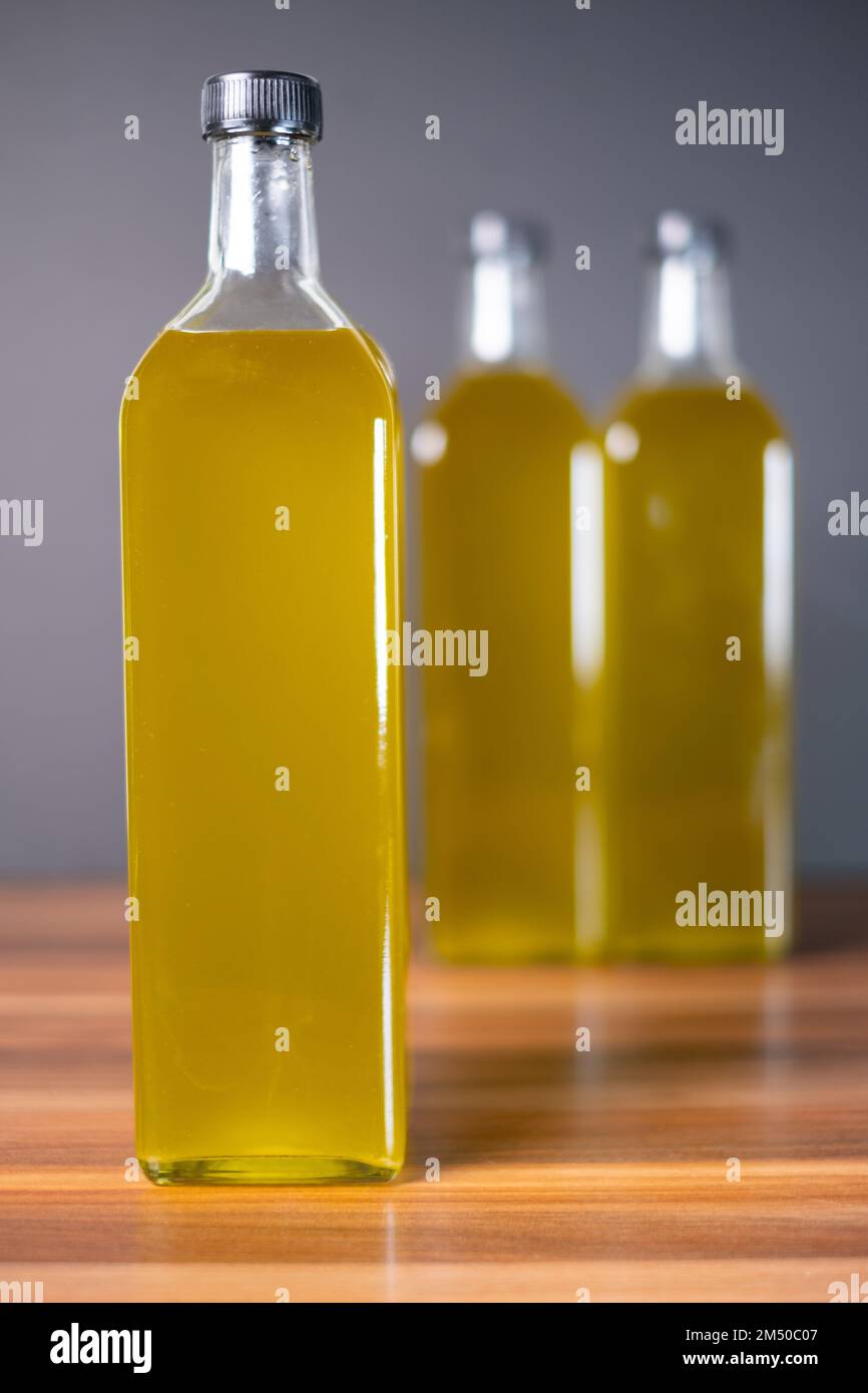 Olivenölflasche auf Holzboden. Natürliches Olivenöl in der Flasche. Stockfoto