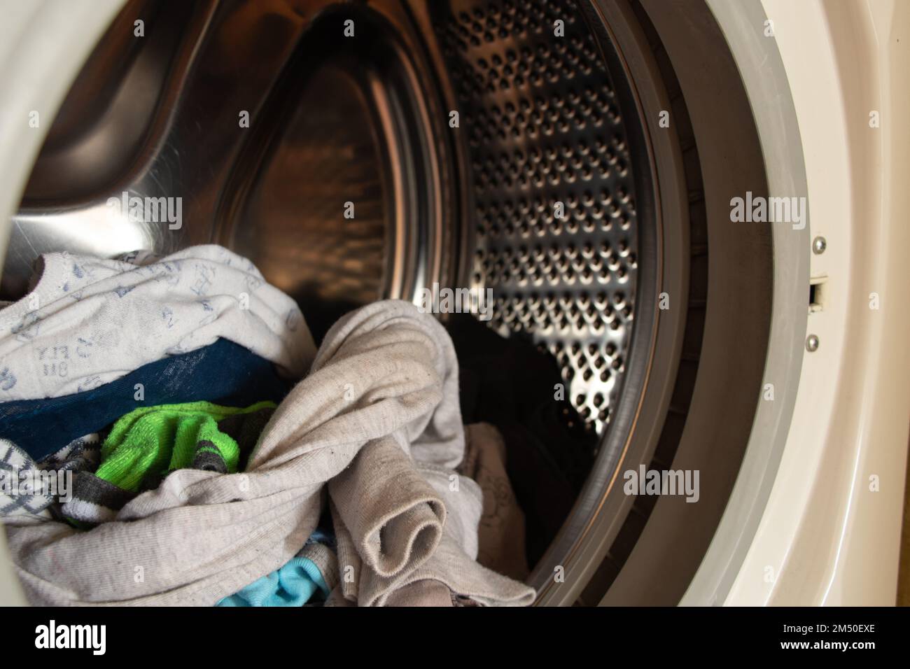Tank in der Waschmaschine mit sauberer Kinderkleidung nach dem Waschen voll füllen Stockfoto