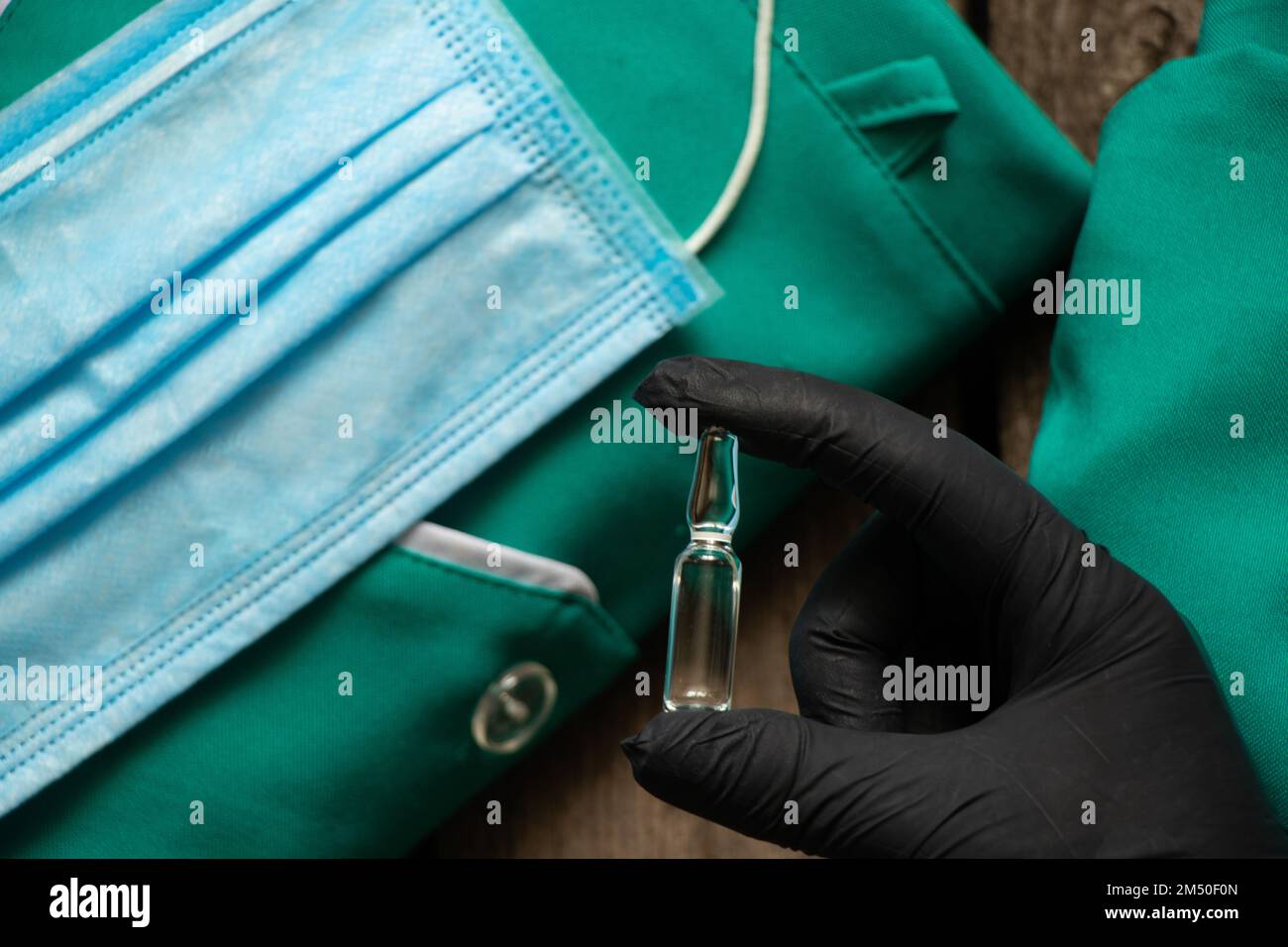 Die Hand in Handschuhen hält eine Ampulle mit Medikamenten Stockfoto