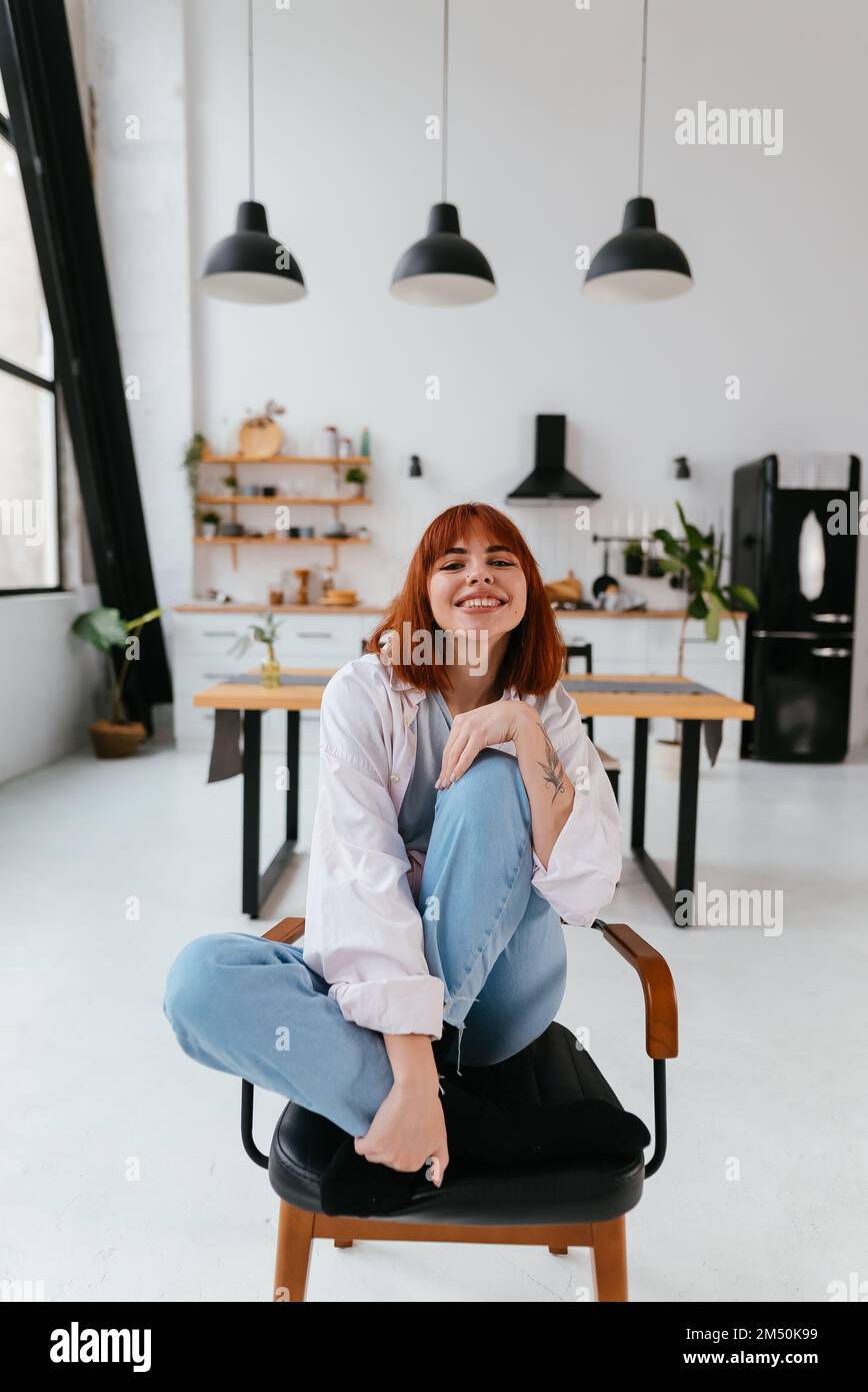 Frau sitzt auf einem Stuhl in einer modernen Küche Stockfoto