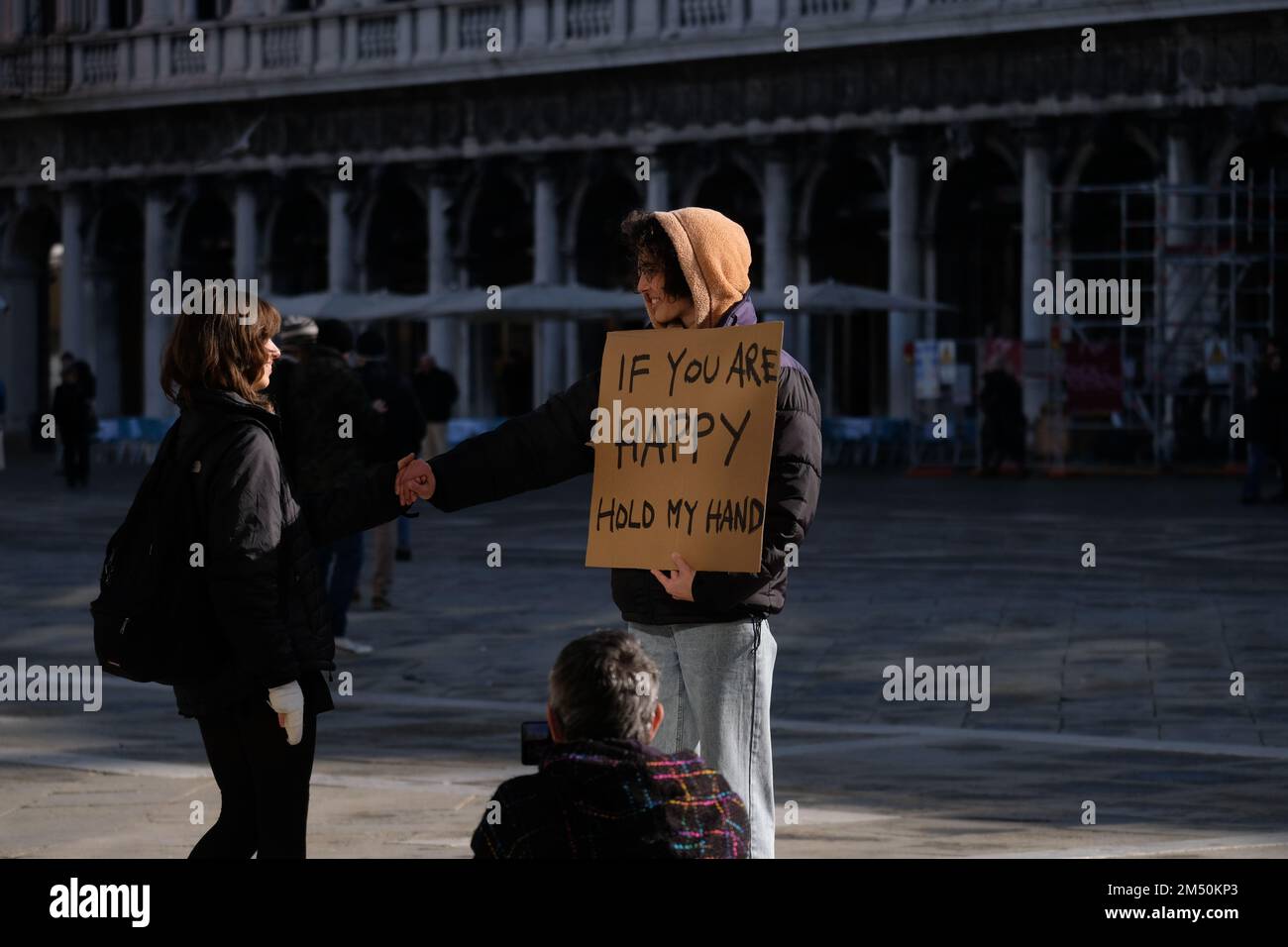 Eine Person am Markusplatz mit einem Schild, wenn Sie zufrieden sind, halten Sie meine Hand. Venedig, Italien, 24. November 2022. Stockfoto