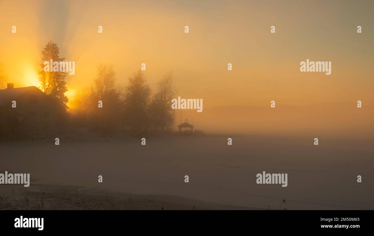 Sonnenuntergang über dem Bysjön-See in Grangärde Schweden mit Nebel über dem Eis auf dem See Stockfoto