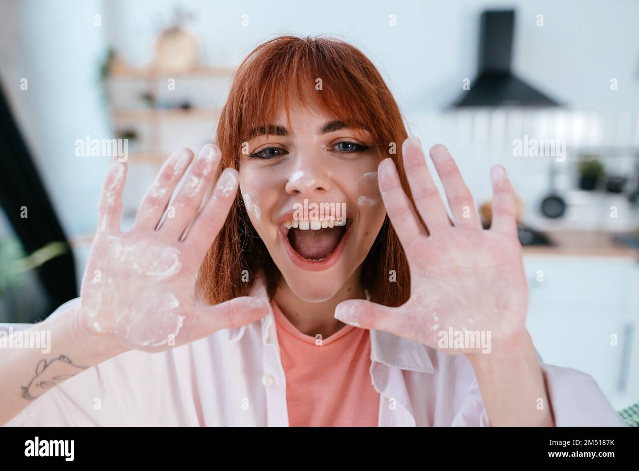 Junge Frau zeigt ihre Hände in Mehl in der Küche Stockfoto