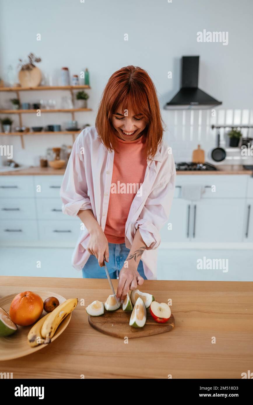 Frau schneidet Früchte auf einem Brett, während sie Frühstück macht Stockfoto