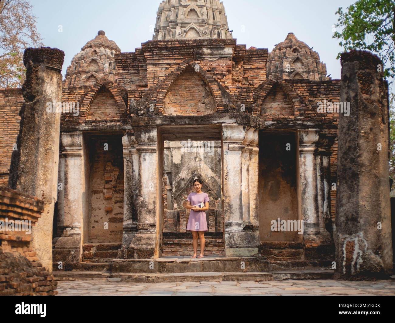 Frau in purpurfarbenem Kleid und altem Tempel in Sukhothai, Thailand im März 13 2021 Stockfoto